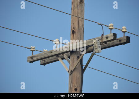 Telefonmast mit Leitungen vor blauem Himmel. Stockfoto