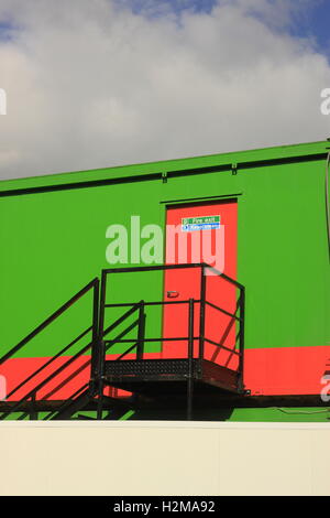 Greenwith rote Brandschutztür in der Sonne gegen graue Wolke Stockfoto