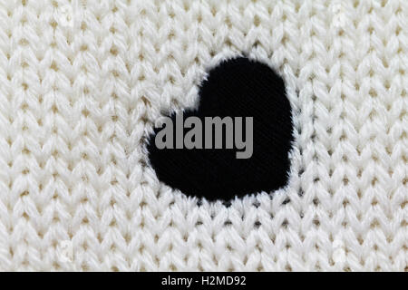 Gestrickte Hintergrund von weißer Farbe mit schwarzen Herzen drauf Stockfoto