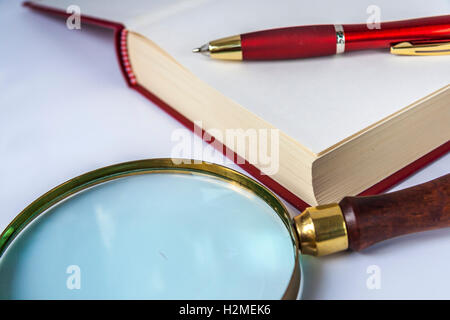 Stift auf das aufgeschlagene Buch liegen und Lupe Stockfoto