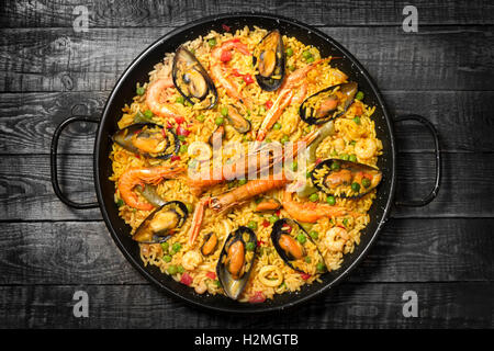 Spanische Paella auf einem dunklen Holztisch Stockfoto