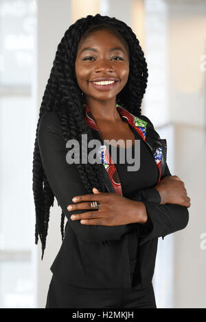 Schöne afrikanische amerikanische Geschäftsfrau lächelnd mit verschränkten im Bürogebäude Stockfoto