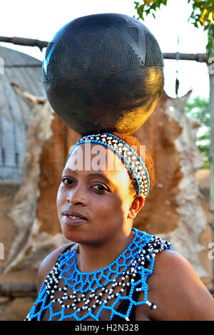 Zulu Mädchen Performer im Shakaland Cultural Village mit einem Wasser - Schüssel auf dem Kopf während eines Zulu Erfahrung, Leistung, Südafrika Stockfoto