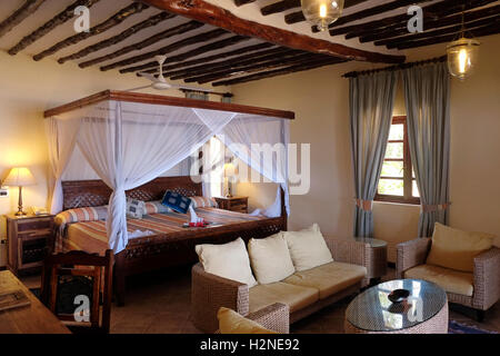Bett mit Moskitonetz Baldachin in einem typischen Zimmer in Blue Bay Hotel in Sansibar Insel, einem halb-autonomen Teil von Tansania, in Ostafrika Stockfoto