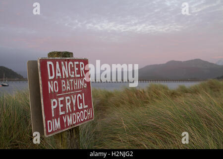 Ein zweisprachiges Schild warnt Badegäste über die Gefahren des Schwimmens in der Mawddach Mündung, North Wales - Schiene Barmouth Netzwerkbrücke hölzerne Viadukt wäre Stockfoto