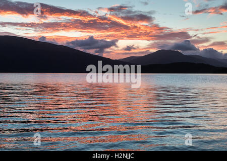 Sonnenuntergang am Loch Lomond, mit den Bergen im Westen des Sees Silhouette Stockfoto