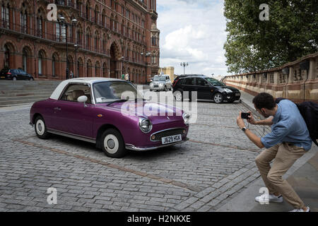 Ein Passant nimmt ein Foto eines Nissan Figaro Autos parkten im Bahnhof St Pancras und Hotel im Norden von London Stockfoto