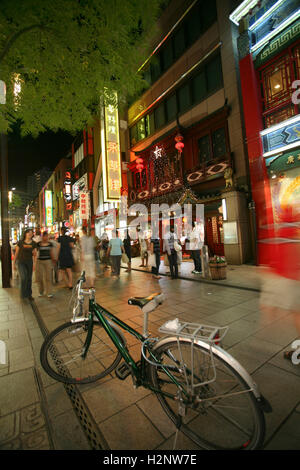 Die Neon-Lichter von den Geschäften und Restaurants in nächtlichen Chinatown, Yokohama, Japan. Fahrrad im Vordergrund Stockfoto