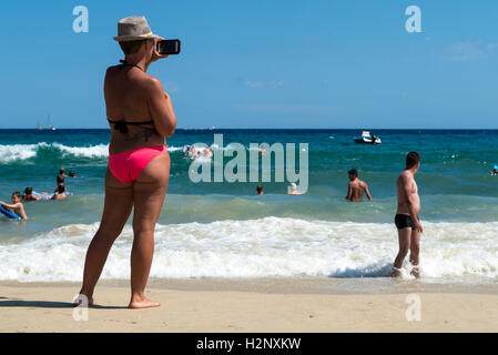 Frau, die ein Bild mit einem Smartphone auf der Region Strand Le Lavandou, Provence-Alpes-Côte d ' Azur, Frankreich Stockfoto