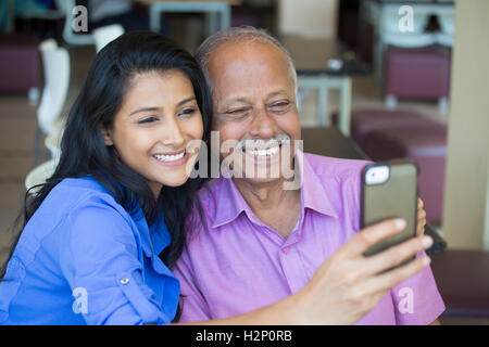 Closeup Portrait glücklich älterer Herr in rosa t-Shirt und Dame in blau oben unter Selfie drinnen zusammen, isolierte Hintergrund. Stockfoto