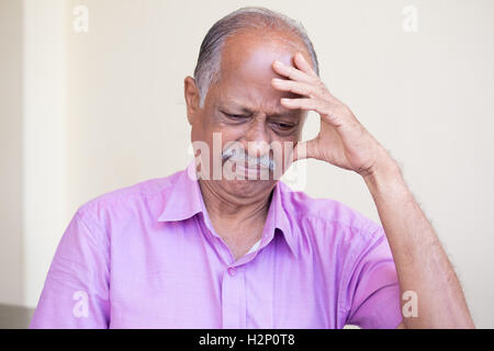 Closeup Portrait, mürrisch ältere Rentner, niedergeschlagen, düster, ruhenden Hand auf Kopf, drinnen zu Hause Hintergrund isoliert. Negative Stockfoto