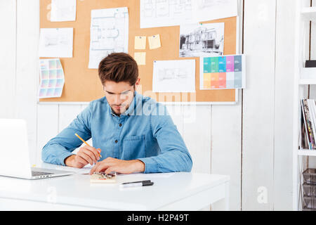 Junge Unternehmer sitzen und schreiben am Tisch im Büro konzentriert Stockfoto