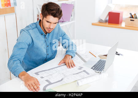 Nachdenklicher junger Geschäftsmann Blick auf Diagramm beim Sitzen am Schreibtisch Stockfoto