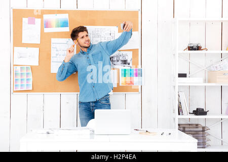 Lächelnde junge Geschäftsmann machen Selfie vor Tafel Büro steht Stockfoto