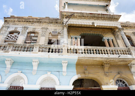 Kubanische Frau mit Lockenwickler im Haar ist aus ihrem Hause Balkon einer kolonialen Gebäude in Santiago De Cuba, Kuba lächelnd. Stockfoto