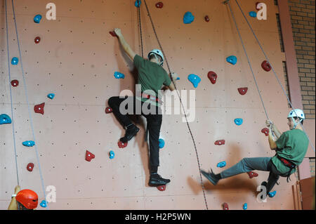 Ein Kletterer macht sich eine Kletterwand, sein Ziel erreichen die Spitze zu erreichen. Stockfoto