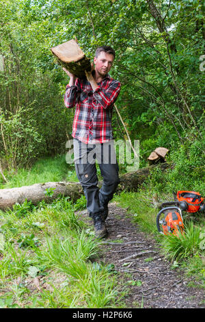 Mann trägt einen Baumstamm Stockfoto