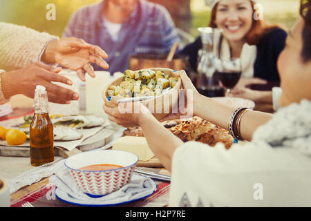 Freunde, die Weitergabe von Nahrung über Terrasse Mittagstisch Stockfoto