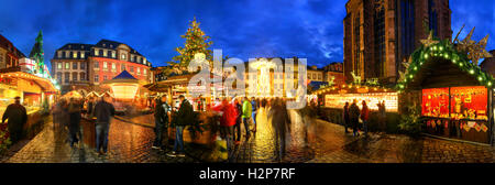 Weihnachtsmarkt in Heidelberg, Deutschland, ein Panorama in der Dämmerung zeigt beleuchtete Kioske, Architektur und unscharfen Menschen erschossen Stockfoto