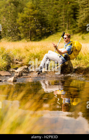 Junge Wanderer sitzen und ruhen neben einem Bergfluss Stockfoto