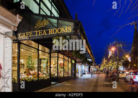 Festliche Weihnachtsdekorationen & Licht in attraktiven Fenster Anzeige An Bettys Café Tea Rooms, dunkle Straße beleuchten - Ilkley, Yorkshire, England, UK. Stockfoto
