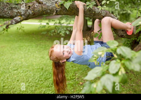 glückliche kleine Mädchen hängen am Baum im Sommerpark Stockfoto