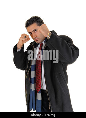 Einen schönen jungen Mann in einem schwarzen Mantel steht für weißen Hintergrund mit den Fäusten auf der Suche nach einem Kampf. Stockfoto