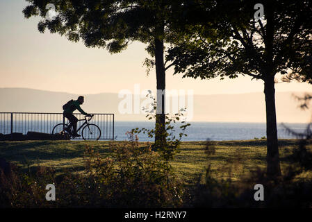 Swansea, Großbritannien. 2. Oktober 2016. UK-Wetter: Ein einsamer Radfahrer macht seinen Weg entlang der Küste bei Blackpill in der Nähe von Swansea heute Morgen kurz nach Sonnenaufgang. Bildnachweis: Phil Rees/Alamy Live-Nachrichten Stockfoto