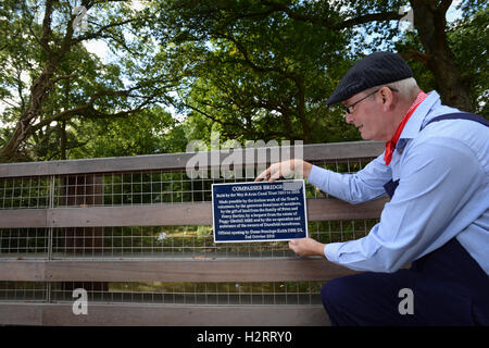 Gekleidet wie ein Kanal Navvy ein Wey & Arun Canal Vertrauen freiwillige behebt eine Gedenktafel an die neue Zirkel-Brücke bei seiner offiziellen Eröffnung auf dem Gipfel auf Alfold, Surrey, England. Die neue Brücke wurde anlässlich des 200. Jahrestages des Kanals im Oktober 2016 eröffnet. Stockfoto