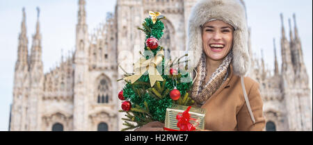 Lustige Weihnachten Reise nach Mailand, Italien. Portrait von lächelnden moderne Frau in Mailand mit Weihnachtsbaum und Geschenk Stockfoto