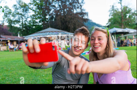 Junger Mann und junge Frau lächelt, Blick auf Handy, Bayern, Deutschland Stockfoto