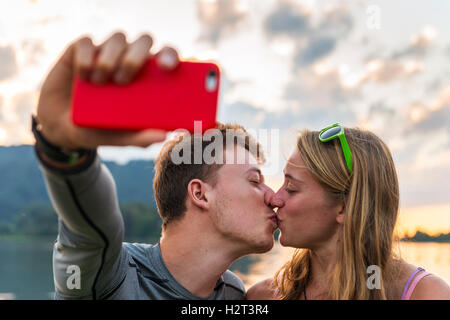 Junges Paar küssen, fotografieren sich mit Handy, Selfie, Schliersee, Upper Bavaria, Bavaria, Germany Stockfoto