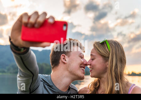 Junges Paar küssen, fotografieren sich mit Handy, Selfie, Schliersee, Upper Bavaria, Bavaria, Germany Stockfoto