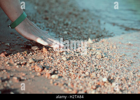 Zarte Frauenhand berühren Strandsand Oberfläche im Vintage-Stil Stockfoto