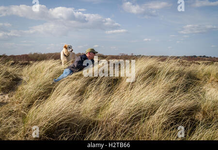 sonniger Wintertag für Mann und Freund golden Retriever in Sanddünen Stockfoto