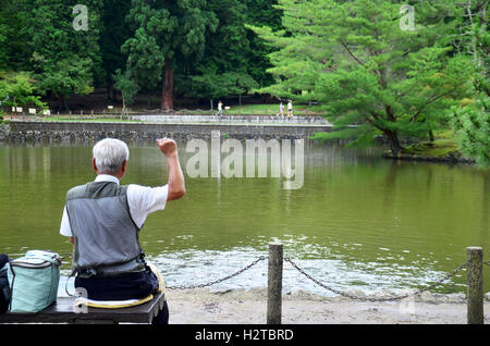 Alter Mann Fütterung Phantasie Karpfen oder Koi Fische im Teich im Garten des Tōdai-Ji Tempel am 9. Juli 2015 in Nara, Japan Stockfoto