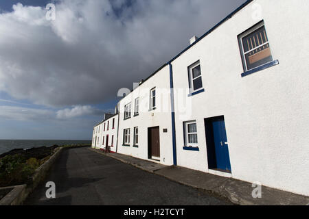 Isle of Islay, Schottland. Malerische Aussicht auf Hütten entlang Ufer Straße in Port Charlotte, mit Loch Indaal im Hintergrund. Stockfoto