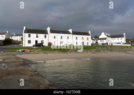 Isle of Islay, Schottland. Auf dem Land entlang Ufer Straße in Port Charlotte, mit dem Strand und dem Pier im Vordergrund. Stockfoto