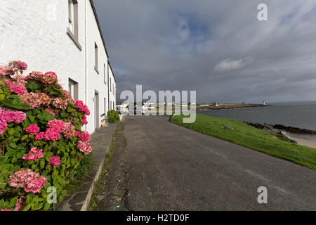 Isle of Islay, Schottland. Malerische Aussicht auf Hütten entlang Ufer Straße in Port Charlotte, mit Loch Indaal im Hintergrund. Stockfoto