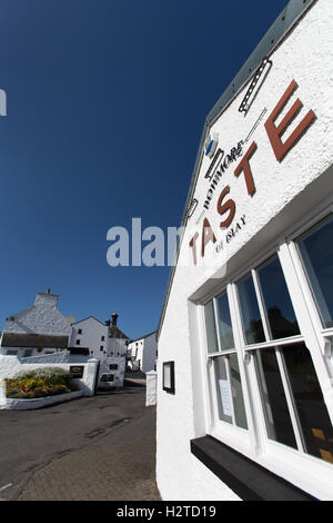 Isle of Islay, Schottland. Malerische Aussicht auf ein Restaurant auf School Street mit der Bowmore Whisky-Destillerie im Hintergrund. Stockfoto