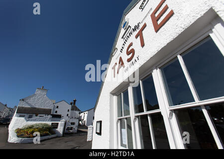 Isle of Islay, Schottland. Malerische Aussicht auf ein Restaurant auf School Street mit der Bowmore Whisky-Destillerie im Hintergrund. Stockfoto