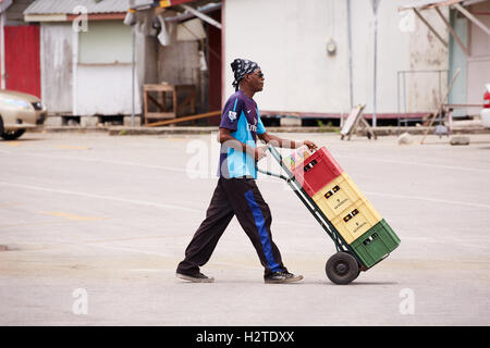 Barbados Fischer Boot Angeln kleine Reggie Farben Farben Hopfen entlassen Wagen mit Bier Kisten lässige schwarze Mann männlich arbeiten Stockfoto