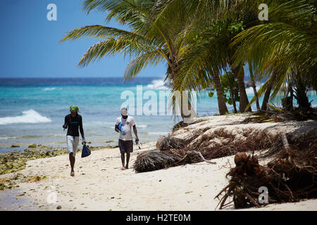 Barbados Hastings Bay Fischer goldenen Sandstrand Palm Bäume Küste zu Fuß Fischer tragen Ruten Stockfoto