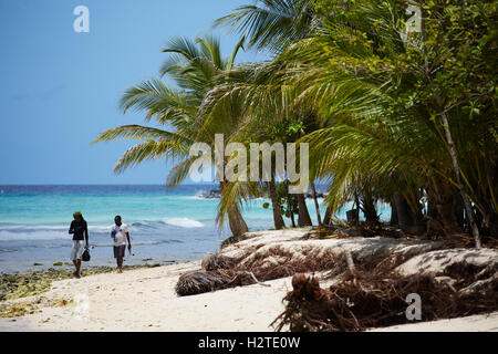 Barbados Hastings Bay Fischer goldenen Sandstrand Palm Bäume Küste zu Fuß Fischer tragen Stangen Exemplar Stockfoto