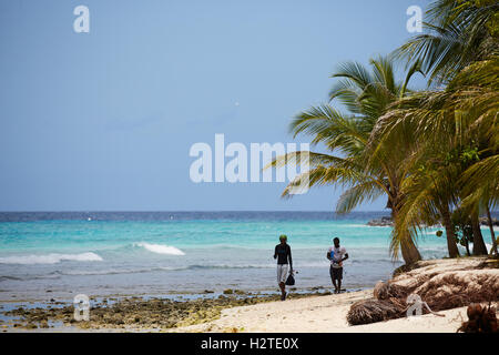 Barbados Hastings Bay Fischer goldenen Sandstrand Palm Bäume Küste zu Fuß Fischer tragen Stangen Exemplar Stockfoto