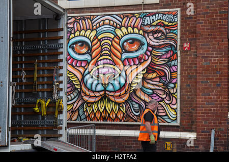 Fußgänger zu Fuß vorbei an Street Art, Graffiti Wand Gesicht Malerei, Dekoration, bei der Sonne, Spray und Art Festival Art in East Topping Street, Blackpool, Lancashire, Großbritannien Stockfoto