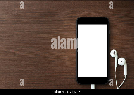 Telefonieren Sie leerer Bildschirm und Kopfhörer auf Holztisch, Mock-up neue Telefon Stil Stockfoto
