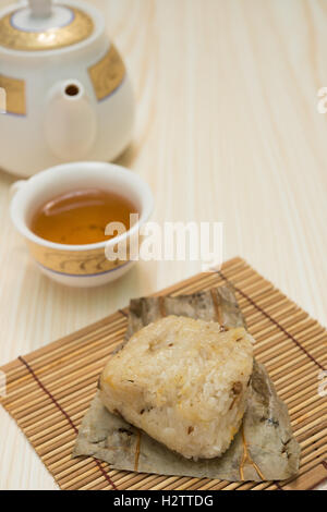 traditionelle chinesische Klebreis Knödel mit Tasse Tee und Teekanne vertikale Zusammensetzung Stockfoto