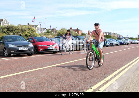 22. Juni 2014, Mann mit dem hellen grünen Fahrrad am Meer entlang an Weston Super Mare, im Sommer. Stockfoto