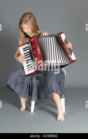 Mädchen mit Schwerpunkt auf spielen Tastenfolge auf dem Akkordeon. Stockfoto